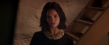 Movie still from “The Exception” (2016), directed by David Leveaux – A young woman with dark brown hair wearing a black dress; Close Up shot, Low angle