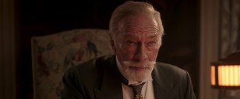 Movie still from “The Exception” (2016), directed by David Leveaux – An older man with a beard and a suit and tie; Close Up shot, Over the shoulder angle