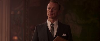 Movie still from “The Exception” (2016), directed by David Leveaux – A man in a suit and tie holding a book; Close Up shot, Low angle