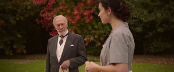 Movie still from “The Exception” (2016), directed by David Leveaux – An older man and a young woman standing next to each other; Medium shot, Over the shoulder angle