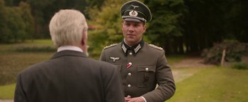 Movie still from “The Exception” (2016), directed by David Leveaux – A man in a uniform talking to a man in a suit; Medium shot, Over the shoulder angle