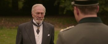 Movie still from “The Exception” (2016), directed by David Leveaux – An older man wearing a suit and tie; Close Up shot, Over the shoulder angle