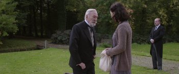 Movie still from “The Exception” (2016), directed by David Leveaux – An older man and a younger woman standing in the grass; Medium shot, Over the shoulder angle