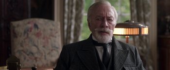 Movie still from “The Exception” (2016), directed by David Leveaux – An older man wearing a suit and a tie; Close Up shot, Over the shoulder angle