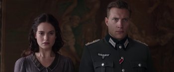Movie still from “The Exception” (2016), directed by David Leveaux – A man and a woman standing next to each other; Close Up shot, Over the shoulder angle