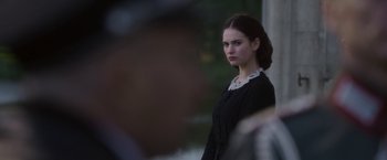 Movie still from “The Exception” (2016), directed by David Leveaux – A woman in a black dress is standing outside; Close Up shot, Over the shoulder angle