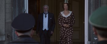 Movie still from “The Exception” (2016), directed by David Leveaux – A man and a woman standing next to each other; Medium shot, Low angle