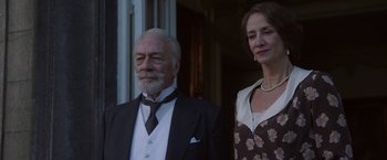 Movie still from “The Exception” (2016), directed by David Leveaux – An older man and a younger woman standing next to each other; Medium shot, Low angle
