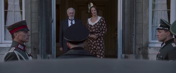 Movie still from “The Exception” (2016), directed by David Leveaux – A man and a woman standing in front of a door; Medium shot, Over the shoulder angle