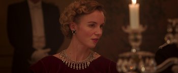 Movie still from “The Exception” (2016), directed by David Leveaux – A woman wearing a red dress and wearing a necklace; Close Up shot, Over the shoulder angle