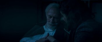 Movie still from “The Exception” (2016), directed by David Leveaux – An older man and a younger woman in a dark room; Close Up shot, High angle
