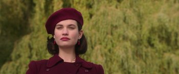 Movie still from “The Exception” (2016), directed by David Leveaux – A woman wearing a red hat and a burgundy coat; Close Up shot, Low angle