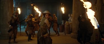 Movie still from “The Extraordinary Adventures of Adèle Blanc-Sec” (2010), directed by Luc Besson – A group of people standing next to fire torches; Wide shot, Over the shoulder angle