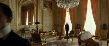 Movie still from “The Extraordinary Adventures of Adèle Blanc-Sec” (2010), directed by Luc Besson – A person standing in a room with a chandelier; Wide shot, Low angle