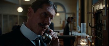 Movie still from “The Extraordinary Adventures of Adèle Blanc-Sec” (2010), directed by Luc Besson – A man in a suit talking on a phone; Close Up shot, Low angle