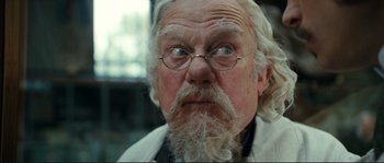 Movie still from “The Extraordinary Adventures of Adèle Blanc-Sec” (2010), directed by Luc Besson – An old man with a long white beard wearing glasses; Close Up shot, Low angle