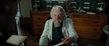 Movie still from “The Extraordinary Adventures of Adèle Blanc-Sec” (2010), directed by Luc Besson – An old man sitting at a desk holding a piece of paper; Medium shot, Low angle