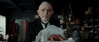 Movie still from “The Extraordinary Adventures of Adèle Blanc-Sec” (2010), directed by Luc Besson – An old man holding a piece of meat in his hands; Close Up shot, Low angle