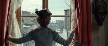 Movie still from “The Extraordinary Adventures of Adèle Blanc-Sec” (2010), directed by Luc Besson – A woman standing in front of a window looking out at a city; Medium shot, Low angle