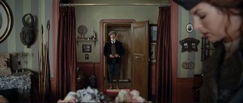 Movie still from “The Extraordinary Adventures of Adèle Blanc-Sec” (2010), directed by Luc Besson – A man standing in front of an open door in a room; Wide shot, High angle