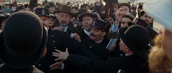 Movie still from “The Extraordinary Adventures of Adèle Blanc-Sec” (2010), directed by Luc Besson – A group of men in hats and coats are gathered together; Medium shot, High angle