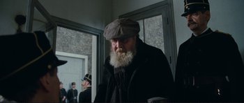 Movie still from “The Extraordinary Adventures of Adèle Blanc-Sec” (2010), directed by Luc Besson – An old man with a beard wearing a hat; Medium shot, Over the shoulder angle
