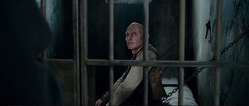 Movie still from “The Extraordinary Adventures of Adèle Blanc-Sec” (2010), directed by Luc Besson – A bald man sitting in a jail cell; Medium shot, High angle