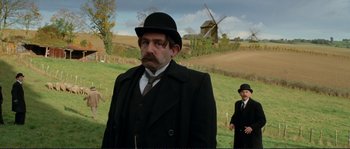 Movie still from “The Extraordinary Adventures of Adèle Blanc-Sec” (2010), directed by Luc Besson – A man in a black suit and a man in a black hat; Medium shot, Over the shoulder angle