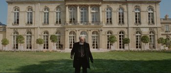 Movie still from “The Extraordinary Adventures of Adèle Blanc-Sec” (2010), directed by Luc Besson – An old man standing in front of a large building; Wide shot, Low angle