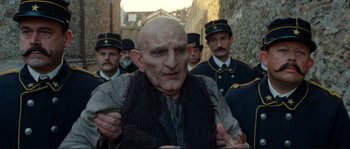 Movie still from “The Extraordinary Adventures of Adèle Blanc-Sec” (2010), directed by Luc Besson – An old man in a vest and a hat is in the middle of a crowd; Medium shot, Over the shoulder angle