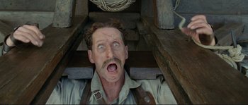 Movie still from “The Extraordinary Adventures of Adèle Blanc-Sec” (2010), directed by Luc Besson – A man with a beard and a mustache is in the middle of a pile of wood; Close Up shot, Overhead angle