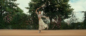 Movie still from “The Extraordinary Adventures of Adèle Blanc-Sec” (2010), directed by Luc Besson – A woman swinging a tennis racquet on a tennis court; Wide shot, Low angle
