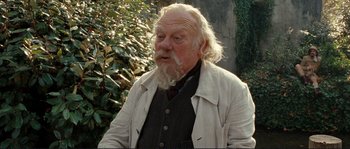 Movie still from “The Extraordinary Adventures of Adèle Blanc-Sec” (2010), directed by Luc Besson – An old man with a beard and white jacket; Close Up shot, Over the shoulder angle