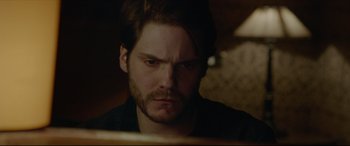 Movie still from “The Face of an Angel” (2014), directed by Michael Winterbottom – A person with a beard looking at the camera; Close Up shot, Over the shoulder angle