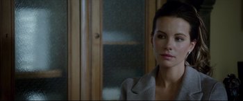 Movie still from “The Face of an Angel” (2014), directed by Michael Winterbottom – A woman in a gray jacket is sitting in front of a wooden door; Close Up shot, Over the shoulder angle