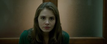 Movie still from “The Face of an Angel” (2014), directed by Michael Winterbottom – A woman with long brown hair sitting in front of a wall; Close Up shot, Over the shoulder angle