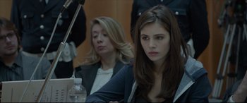 Movie still from “The Face of an Angel” (2014), directed by Michael Winterbottom – A woman sitting next to another woman in a courtroom; Close Up shot, Over the shoulder angle