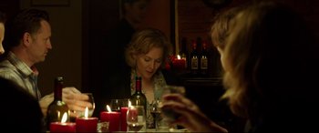 Movie still from “The Face of an Angel” (2014), directed by Michael Winterbottom – A woman sitting at a table with a glass of wine; Medium shot, Over the shoulder angle