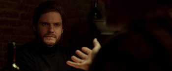 Movie still from “The Face of an Angel” (2014), directed by Michael Winterbottom – A man sitting in front of another man in front of a brick wall; Close Up shot, Over the shoulder angle