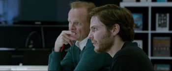 Movie still from “The Face of an Angel” (2014), directed by Michael Winterbottom – Two men sitting next to each other in front of a wall; Close Up shot, Over the shoulder angle