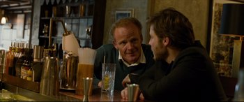 Movie still from “The Face of an Angel” (2014), directed by Michael Winterbottom – Two men sitting at a table talking to each other; Medium shot, Over the shoulder angle