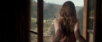 Movie still from “The Face of an Angel” (2014), directed by Michael Winterbottom – A woman looking out of a window at a field; Medium shot, Over the shoulder angle