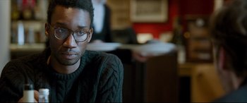 Movie still from “The Face of an Angel” (2014), directed by Michael Winterbottom – A man wearing glasses sitting in a room; Close Up shot, Over the shoulder angle
