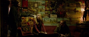 Movie still from “The Face of an Angel” (2014), directed by Michael Winterbottom – A woman sitting on top of a red couch next to a man; Medium shot, Low angle