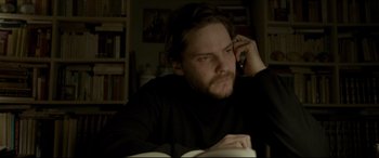 Movie still from “The Face of an Angel” (2014), directed by Michael Winterbottom – A man sitting at a table talking on a cell phone; Close Up shot, High angle