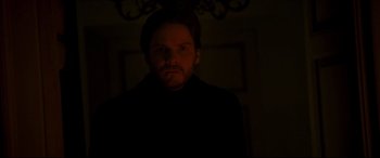Movie still from “The Face of an Angel” (2014), directed by Michael Winterbottom – A man in a dark room looking at the camera; Close Up shot, Low angle