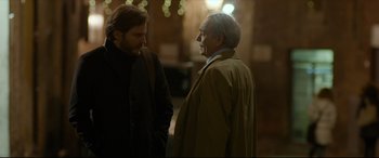 Movie still from “The Face of an Angel” (2014), directed by Michael Winterbottom – Two men are standing next to each other talking; Medium shot, Over the shoulder angle