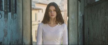 Movie still from “The Face of an Angel” (2014), directed by Michael Winterbottom – A woman in a white shirt standing in front of a building; Medium shot, Low angle