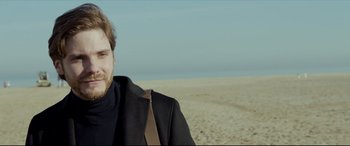 Movie still from “The Face of an Angel” (2014), directed by Michael Winterbottom – A person wearing a suit and tie on the beach; Close Up shot, Low angle