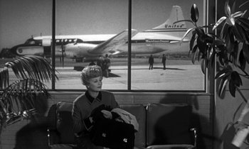 Movie still from “The Facts of Life” (1960), directed by Melvin Frank – A woman sitting in front of an airplane window; Wide shot, Low angle